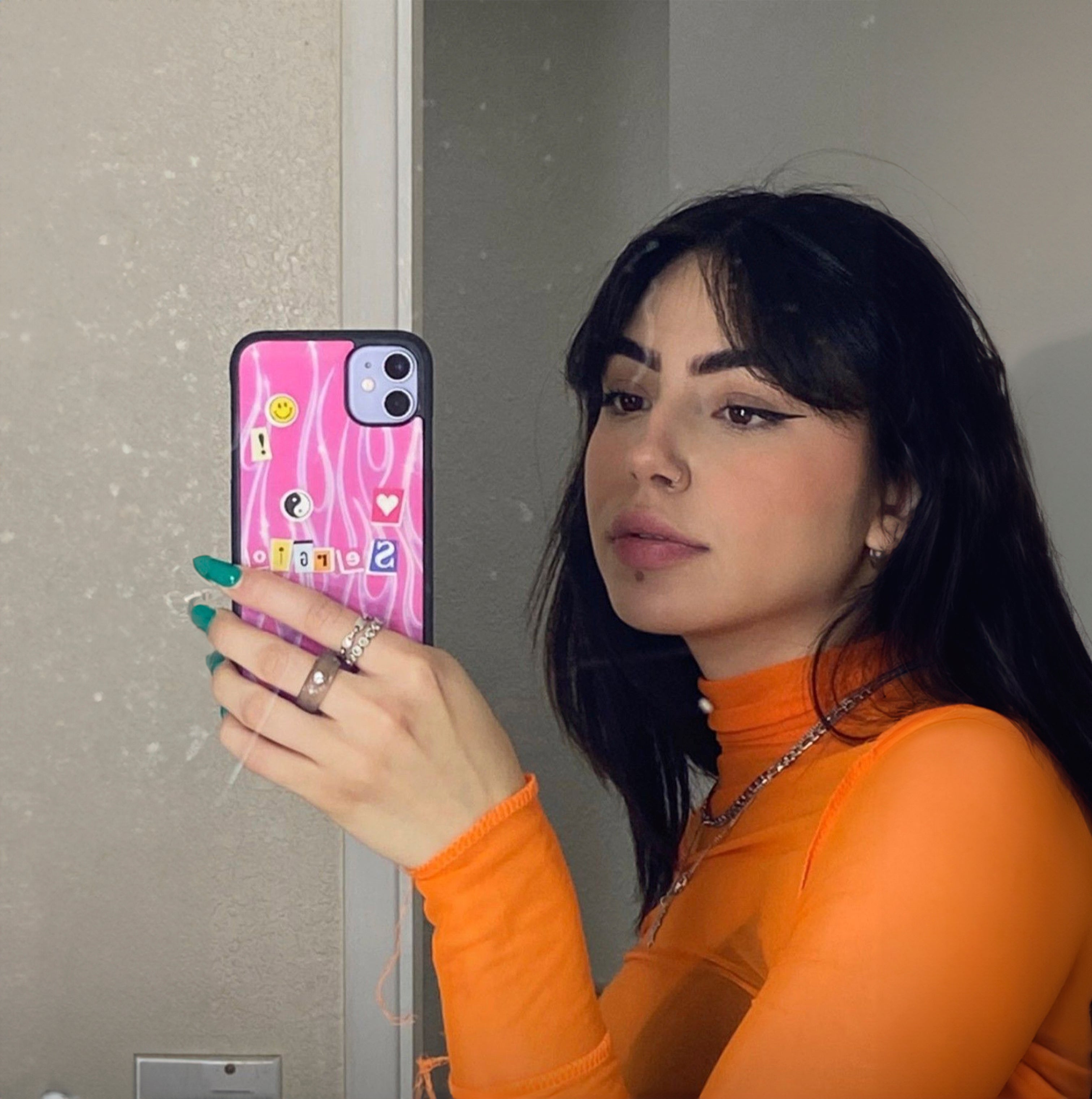 A pretty girl with a custom iPhone 11 phone case taking a mirror selfie.